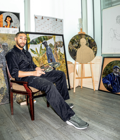 artist Joshua Donkor seated in studio with paintings