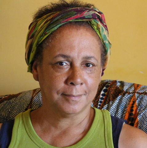 portrait of artist Vivian in head wrap and yellow background